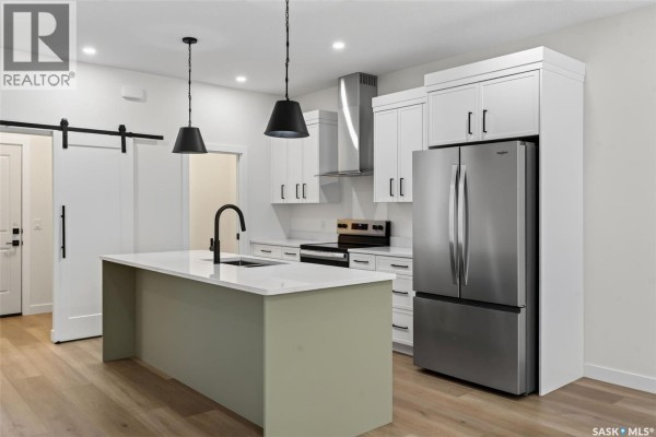 Kitchen featuring a large island with a sink, white cabinets, and stainless steel refrigerator. - 1006 10th Street, Humboldt