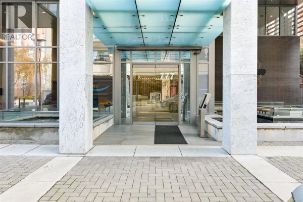 Modern glass and stone building entrance with automatic doors and paved walkway. - 1006 777 Herald St, Victoria