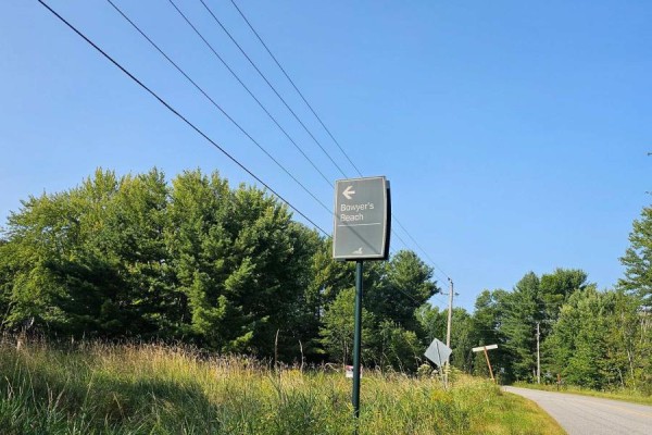 Gravel driveway leading to a cleared area with a pile of sand and surrounding trees. - 1006 Bowyers Beach Road, Bracebridge)