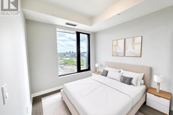 Bedroom with a king-size bed, nightstands, and a large window with a view. - 1007 - 3006 William Cutmore Boulevard, Oakville