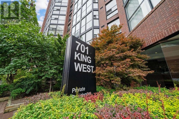 Black sign with "701 KING WEST" and "Private Residences" text on a landscaped garden. - 1007 - 701 King Street W, Toronto