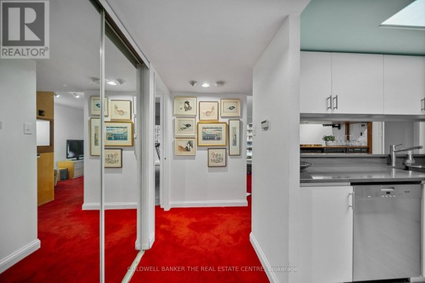 Hallway with red carpet, mirrored closet doors, and artwork displayed on white walls. - 1007 - 701 King Street W, Toronto