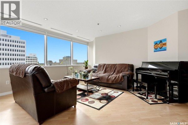 Living room with a piano, sofas, coffee table, rug, and expansive city views. - 1007 1914 Hamilton Street, Regina