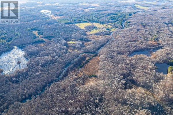 Aerial view of the property with a white polygon outlining the land boundaries, showing distant fields. - 1007 Mount Stephen Road Ne, Severn