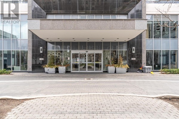 Entrance to a modern condominium building with large glass doors and planters. - 1008 - 120 Harrison Garden Boulevard, Toronto