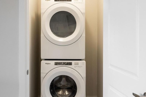 Stacked white Whirlpool washer and dryer in a closet with a white door. - 1008 - 4286 King Street, Kitchener