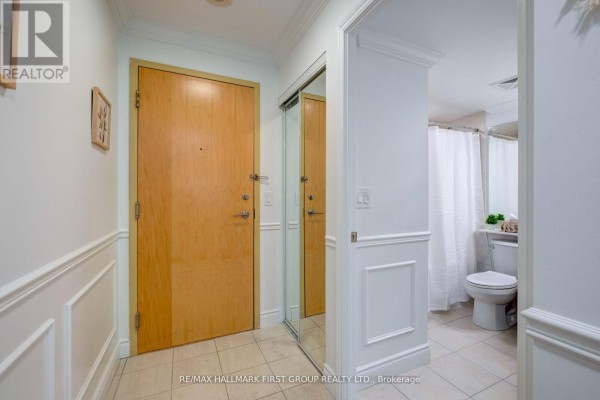 Apartment entryway with a light wood door, mirrored closet, and tiled floor. - 1008 - 60 Brian Harrison Way, Toronto