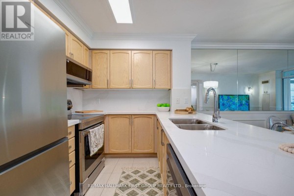 Kitchen view showing stainless steel appliances, white countertops, and light wood cabinets. - 1008 - 60 Brian Harrison Way, Toronto