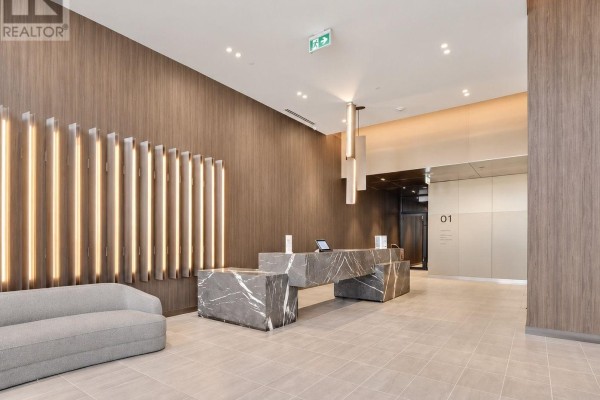 Modern lobby with wood paneling, contemporary reception desk, and linear lighting. - 1008 - 91 John Street, Hamilton