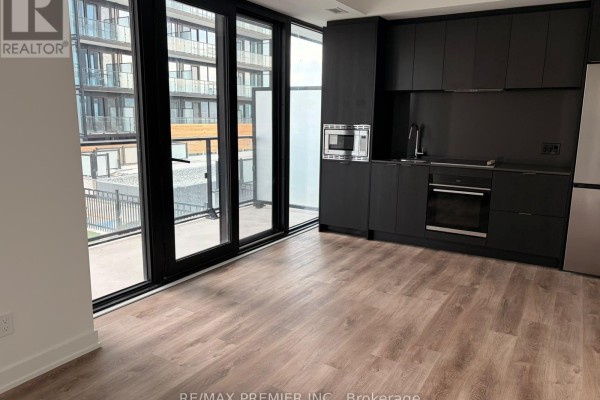 Apartment living area with dark cabinetry, stainless steel appliances, and a balcony view. - 1008 - 91 John Street, Hamilton