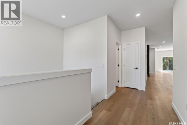 Hallway with hardwood floors, white walls, and doors leading to rooms. - 1008 10th Street, Humboldt