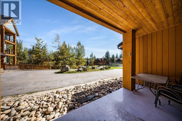 View from a covered patio with outdoor seating and a gravel pathway. - 1008 Olaus Way Unit# 2, Rossland