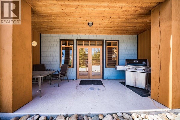 Ground floor patio with a gas grill, table, chairs, and double glass doors. - 1008 Olaus Way Unit# 2, Rossland