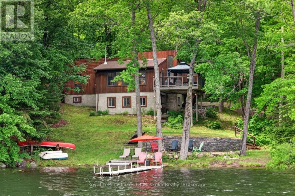 Exterior of a wood-sided house on a slope with a dock and lake access. - 1008 Seven Dwarfs Crescent, Bracebridge
