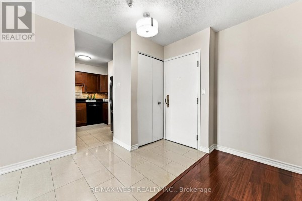 Apartment entryway with cream walls, white trim, light beige floor tiles, and a doorway to the kitchen. - 1009 - 1320 Islington Avenue, Toronto