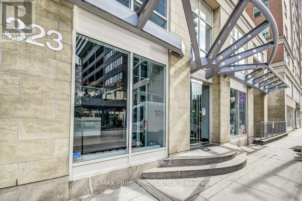 Spacious lobby with a metal spiral staircase, glass entrance, and seating. - 1009 - 323 Richmond Street, Toronto