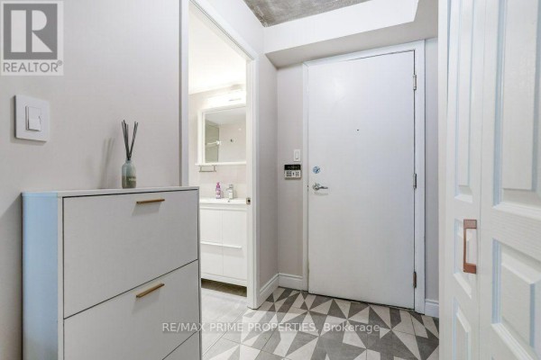 Long, well-lit apartment building hallway with black doors and textured walls. - 1009 - 323 Richmond Street, Toronto