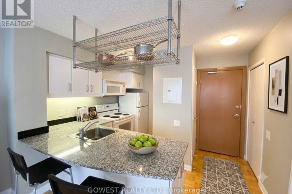 Kitchenette with granite countertops, white cabinets, stove, refrigerator, and pendant lighting. - 1009 - 33 Sheppard Avenue E, Toronto