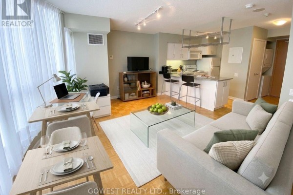 Living area with sofa, coffee table, dining set, and desk area with laptop. - 1009 - 33 Sheppard Avenue E, Toronto