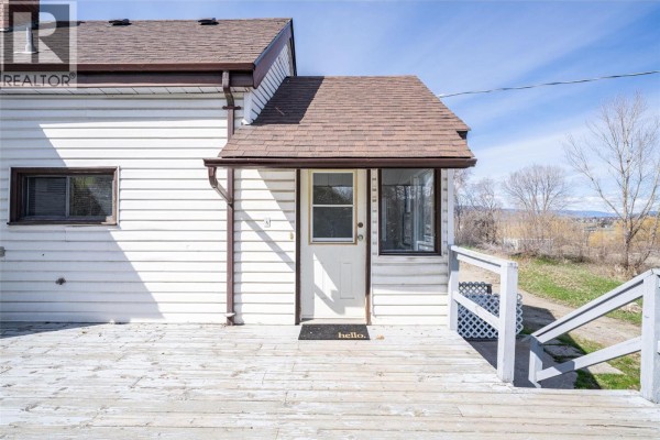Interior view of a small sunroom with windows, a door, a refrigerator, and a rug. - 10091 6 Highway, Coldstream