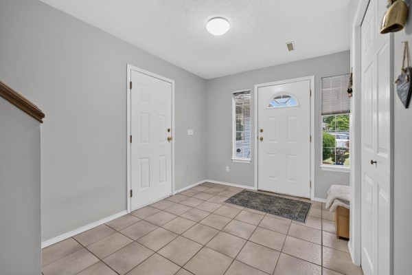 Foyer with staircase, white doors, and decorative cabinet. - 10097 Beaver Crescent, Little Mountain, Chilliwack