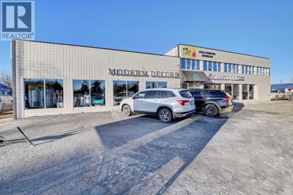 Commercial building exterior with "Modern Decor" and "Carpet One" signage, parked vehicles - 101, 10404 100 Street, Grande Prairie