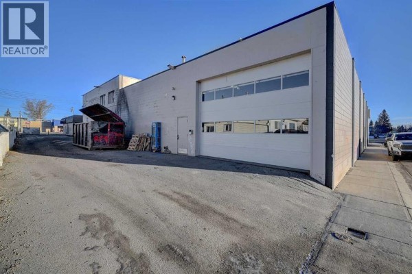 Rear exterior of commercial building with a large bay door and dumpster - 101, 10404 100 Street, Grande Prairie