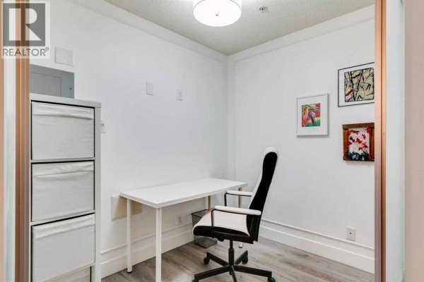 Small office room with a white desk, office chair, storage cubes, and artwork. - 101, 1521 26 Avenue Sw, Calgary