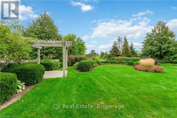 Manicured garden with green lawn, shrubs, and a wooden pergola on a sunny day. - 101 - 10 Bay Street, Blue Mountains