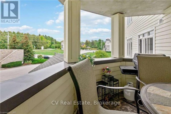 Balcony with seating, a grill, and propane tank overlooking a street with houses. - 101 - 10 Bay Street, Blue Mountains