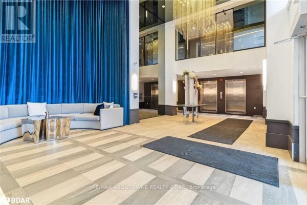 Building lobby with a grey sectional sofa and decorative blue curtains. - 101 - 10 Concord Place, Grimsby