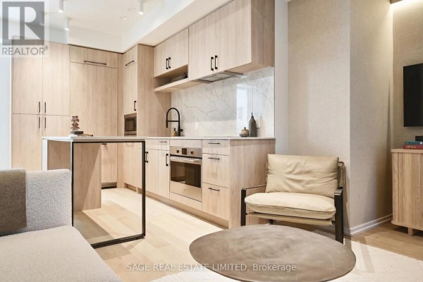 Interior view of a modern kitchen and living area with light wood cabinetry and furniture. - 101 - 109 Erskine Avenue, Toronto