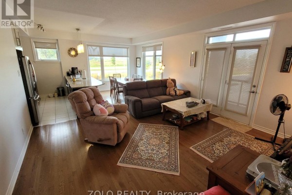 Open concept living area with kitchen, dining table, and sofa near patio doors. - 101 - 130 Guelph Private, Ottawa