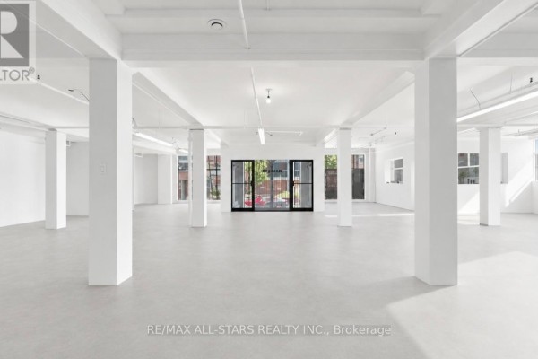 Wide view of an empty commercial interior with light beige flooring and white walls. - 101 - 14 Mccaul Street, Toronto
