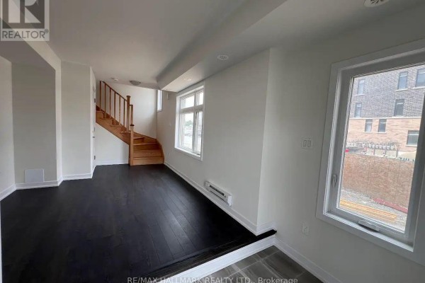 Living room with beige sofa and rug, coffee table, and view of the kitchen. - 101 - 1865 Pickering Parkway S, Pickering