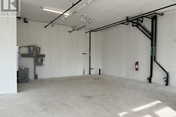 Unfinished commercial space with concrete floor, white walls, and large windows showing exterior. - 101 - 2370 Tenth Line Road, Ottawa