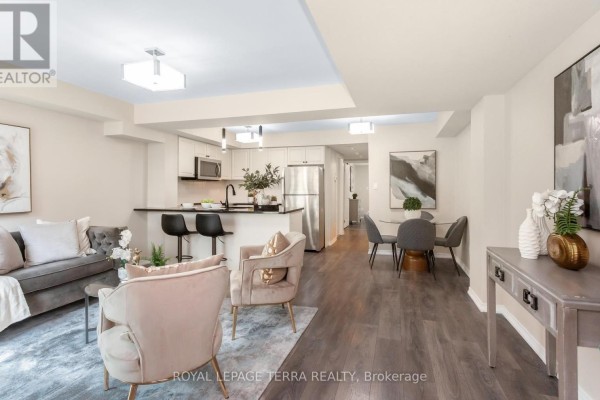 Open-concept living space with a kitchen island, dining area, and living room furniture. - 101 - 3 Applewood Lane, Toronto