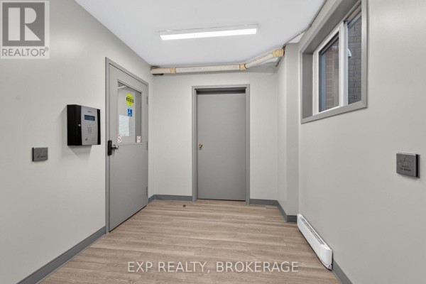 Interior hallway with light gray walls, laminate flooring, and two doors. - 101 - 316 Kingsdale Avenue, Kingston