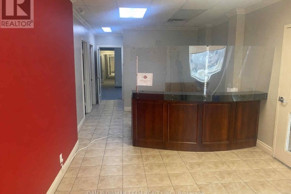Reception desk with plexiglass divider and hallway view. - 101 - 360 King Street W, Oshawa