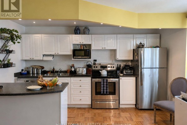 Kitchen with white cabinets, stainless steel appliances, and light wood flooring. - 101 - 4 Sherbourne Street N, Toronto