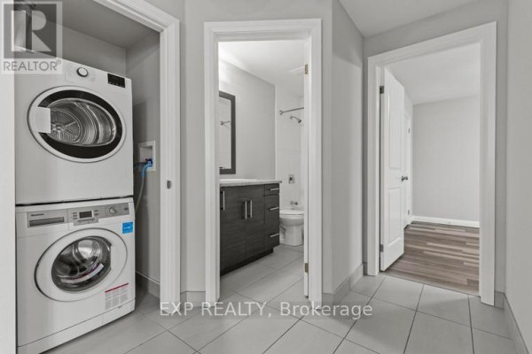 Hallway with stacked washer and dryer, a vanity, and a doorway to another room. - 483 Linwell Road, St  Catharines
