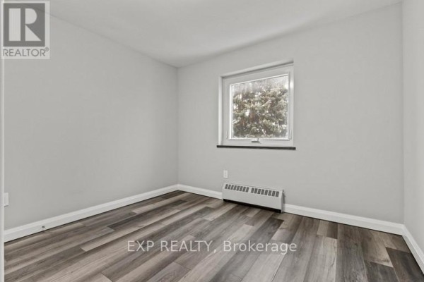 Small bedroom with light gray walls, wood-look flooring, and a single window. - 483 Linwell Road, St  Catharines