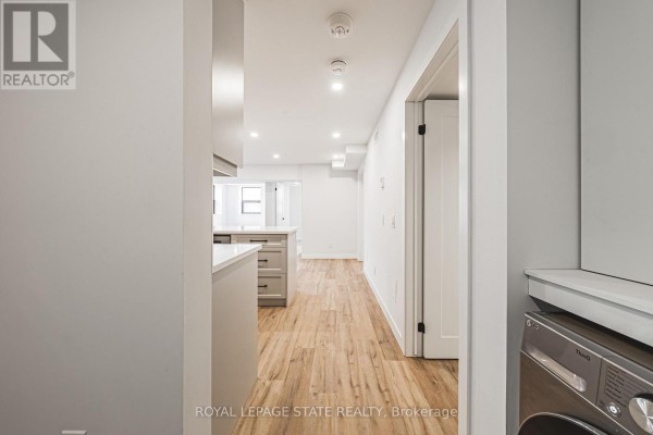 Hallway view into an apartment showing a laundry area, kitchen, and living space. - 101 - 555 Sanatorium Road, Hamilton