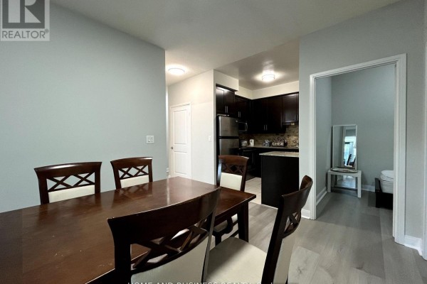 Dining table and chairs with view into dark wood kitchen and hallway. - 101 - 80 Absolute Avenue, Mississauga
