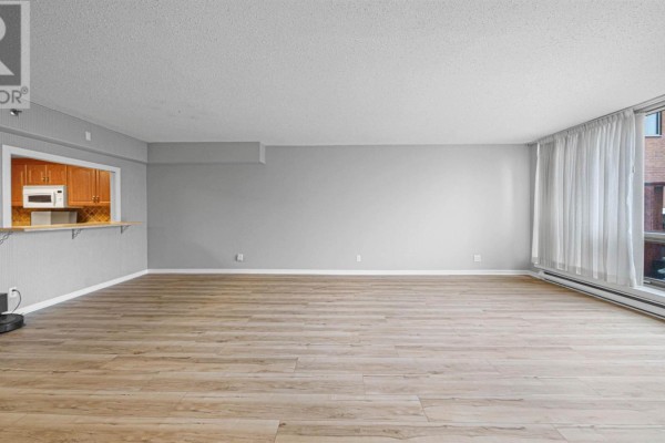 Spacious living area with light wood floors and a kitchen pass-through. - 101 1 Prince Street, Dartmouth