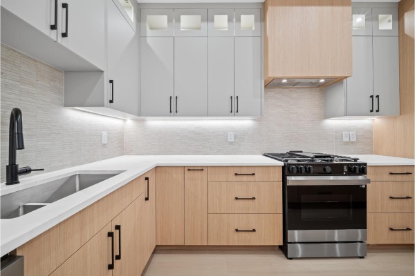 Spacious open-concept kitchen featuring a large white island, light wood cabinetry, and stainless steel appliances. - 101 11480 138a Street, Surrey