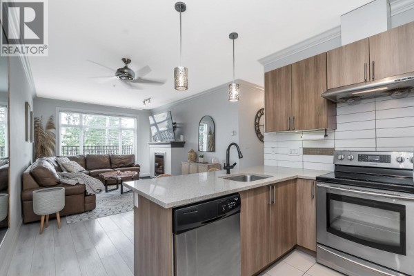 Open concept living area and kitchen with a leather sofa and island. - 101 11566 224 Street, Maple Ridge