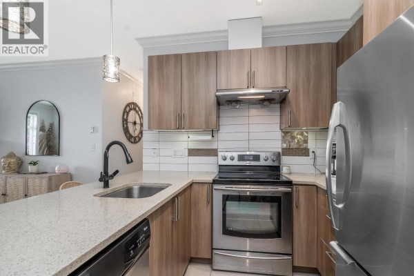 Modern kitchen with light wood cabinets, granite countertops, and stainless steel appliances. - 101 11566 224 Street, Maple Ridge