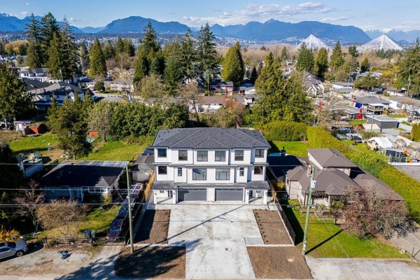Aerial view of a new duplex building with surrounding houses and distant mountains. - 101 14259 Park Drive, Surrey