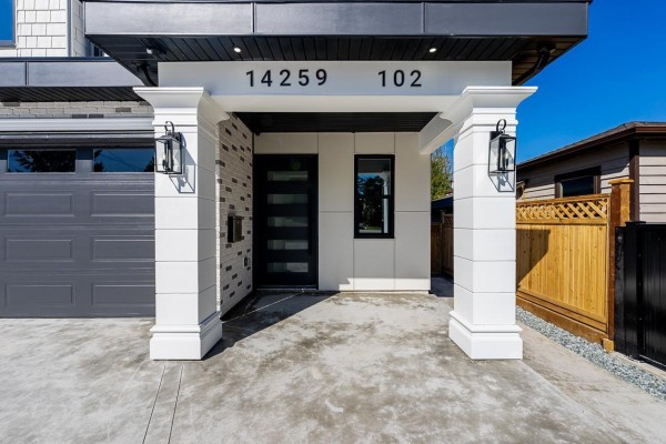 Close-up of the duplex entrance with white columns, modern lighting, and a dark grey garage. - 101 14259 Park Drive, Surrey